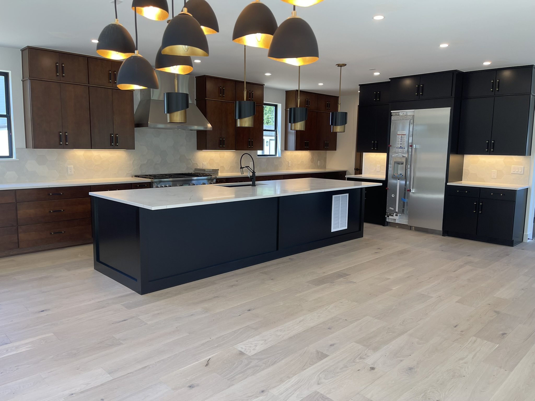 Modern kitchen with large island and pendant lights.