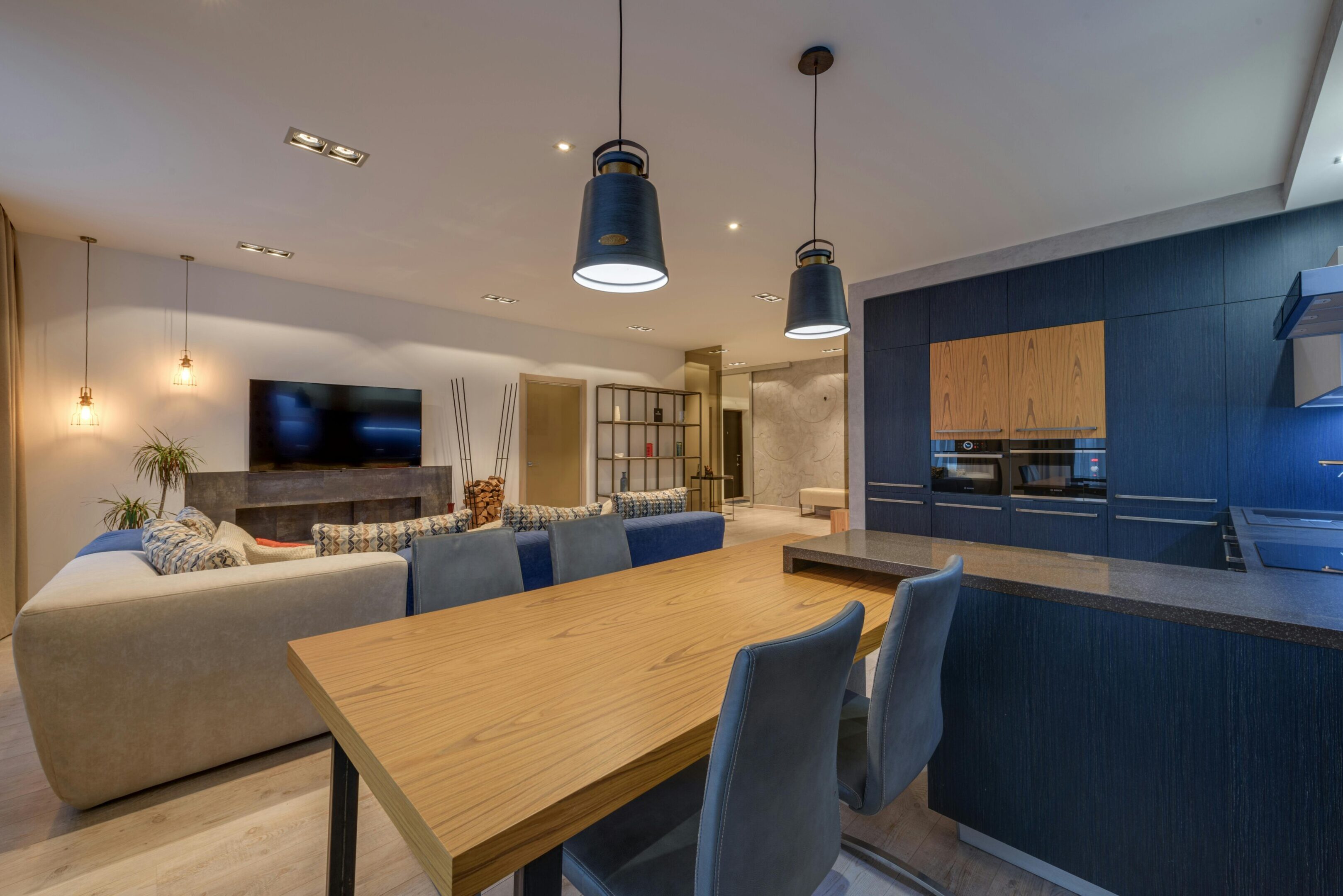 Modern dining area with wooden table and pendant lights.