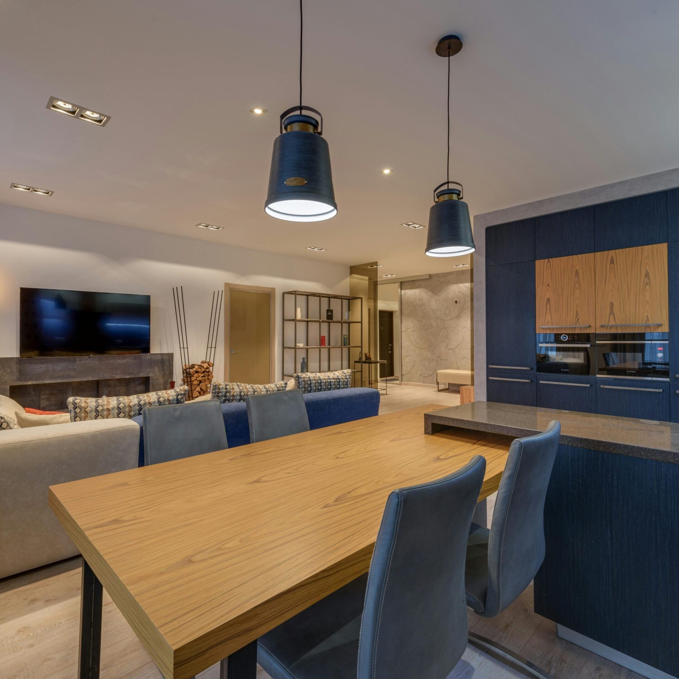 Modern dining area with wooden table and pendant lights.